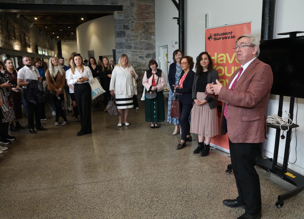 Photograph of attendees at Practitioners Forum standing in a semi-circle listening to Ciarán Ó hÓgartaigh